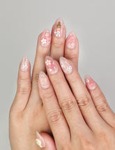 Hand wearing Naillover Bunny Blush handmade press on nails in soft pink with rabbit and floral designs accented by gold details.